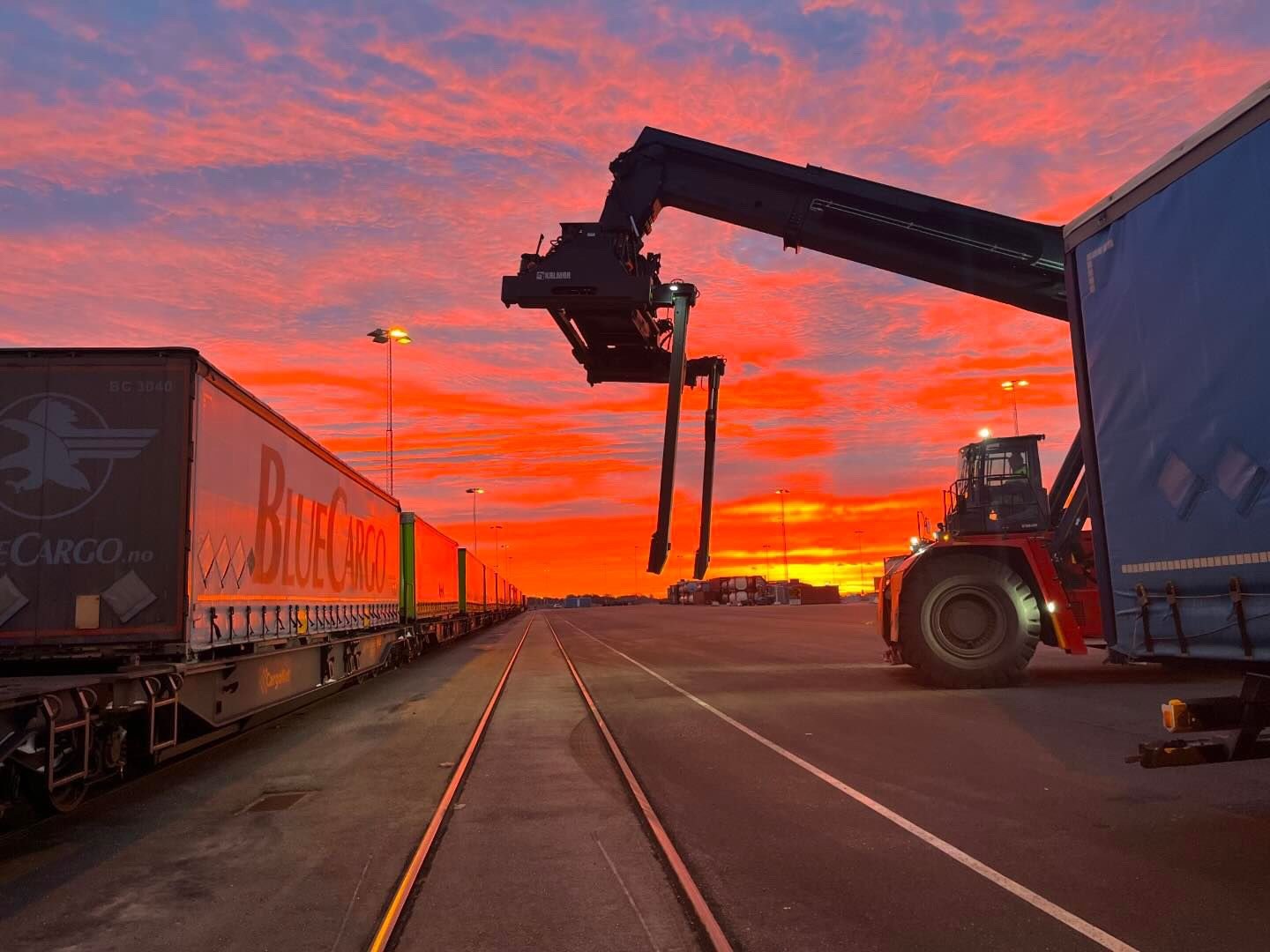 Intermodal terminal, Trelleborg: reach stacker and rail wagons at sunset